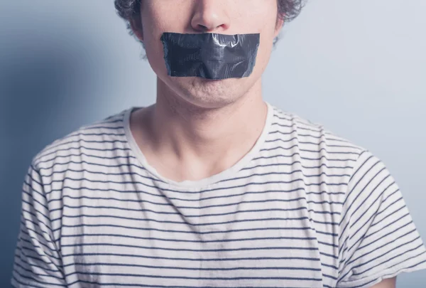 Jonge man met tape die betrekking hebben op zijn mond — Stockfoto