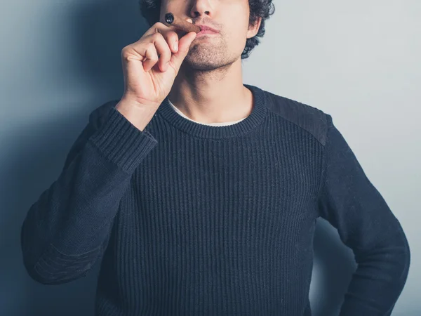 Молодой человек курит сигару — стоковое фото