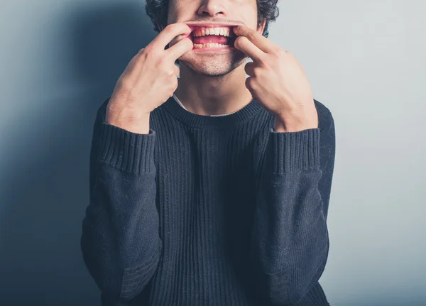 Giovane uomo che tira facce stupide — Foto Stock