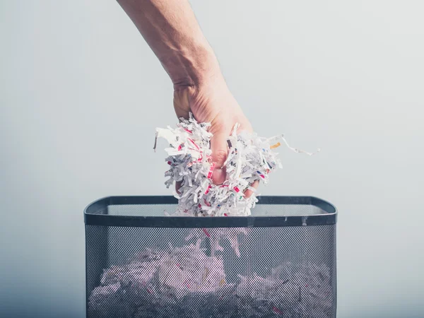 Hand putting shredded paper in basket — Stock Photo, Image