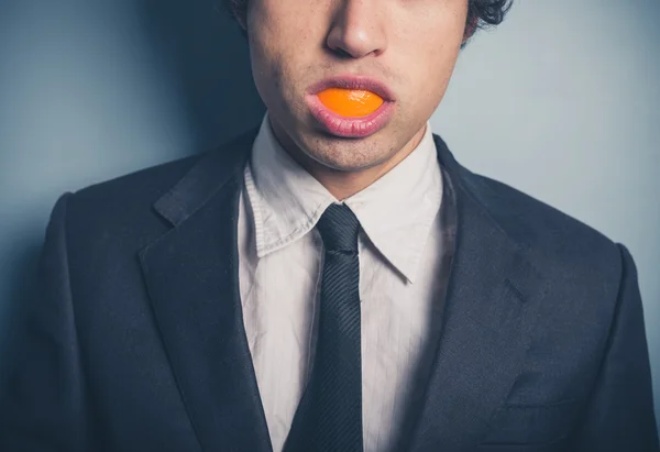 Empresário com casca de laranja na boca — Fotografia de Stock