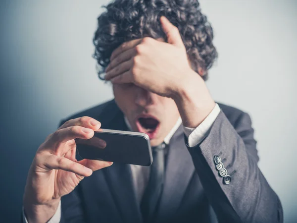 Geschockter Geschäftsmann liest auf seinem Smartphone — Stockfoto