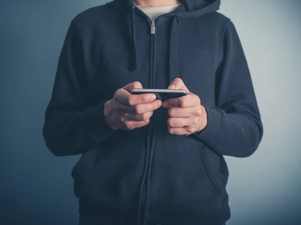 Mann in Kapuzenpulli benutzt sein Smartphone — Stockfoto