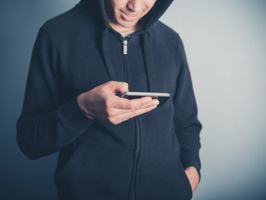 Erkek Kapşonlu üst onun smartphone kullanarak