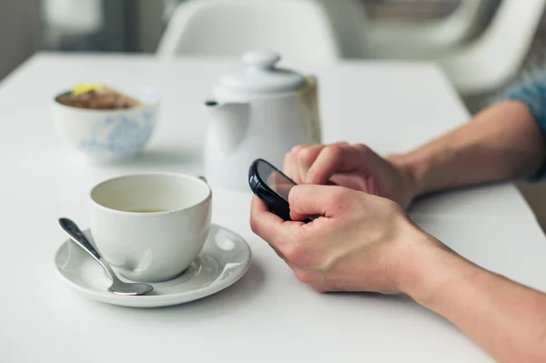 Woman using phone and having tea — Stock Photo, Image