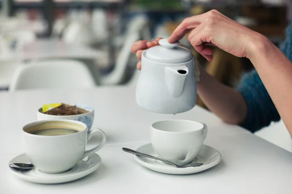 Jovem mulher derramando uma xícara de chá — Fotografia de Stock