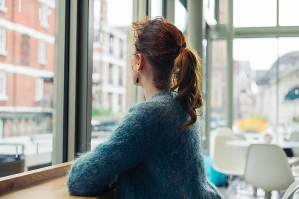 Mujer joven sentada mirando por la ventana —  Fotos de Stock