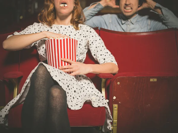 Woman annoying man in cinema by eating popcorn — Stock Photo, Image