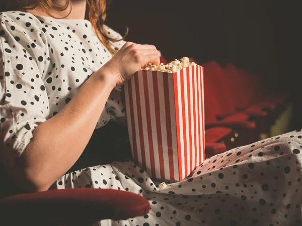 Молодая женщина ест попкорн в кинотеатре — стоковое фото