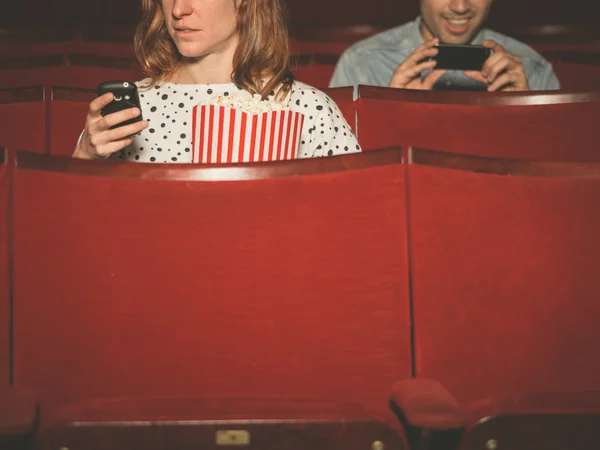 Uomo e donna che usano i loro telefoni in teatro — Foto Stock