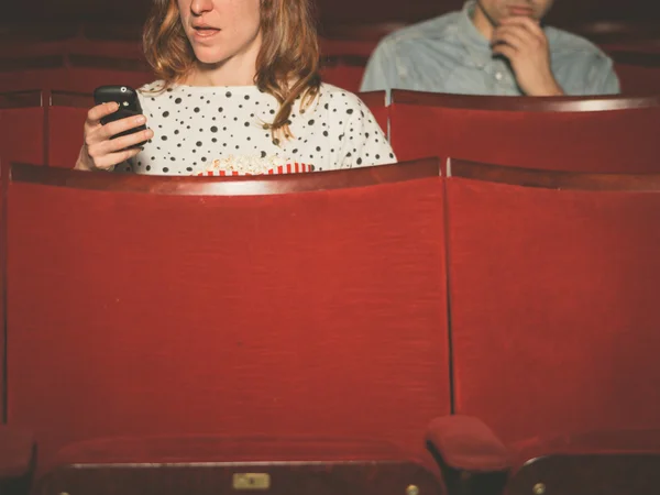 Vrouw met behulp van haar telefoon in theater — Stockfoto