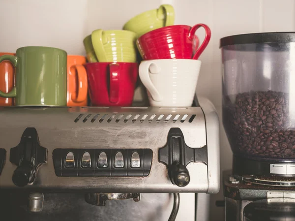 Kávovar a barevné kelímky — Stock fotografie