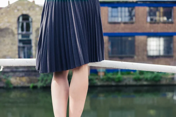 Woman wearing skirt standing on bridge by canal — Stock Photo, Image