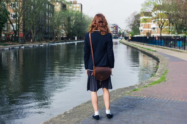 Vrouw in rok en jasje schuren door kanaal — Stockfoto