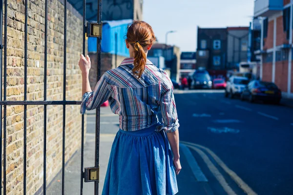 Woman standing in street by gate — Stock Photo, Image