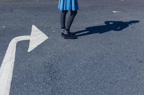 Woman standing outside by big arrow — Stock Photo, Image