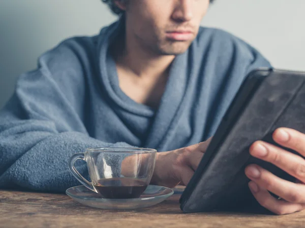 Man in bathrobe having coffee and using tablet — Stock Photo, Image