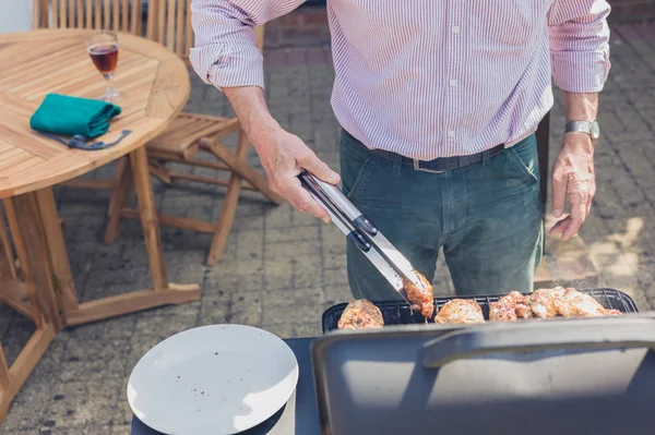 Senior man doing barbecue in garden — Stock Photo, Image