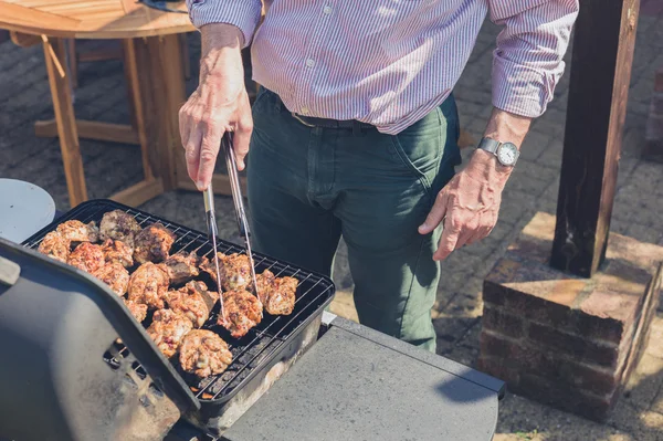Senior man grilling meat on barbecue — Stock Photo, Image