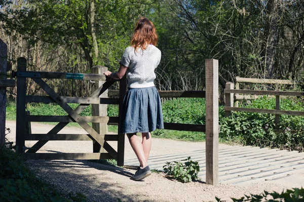 Kobieta stojąc przez bramę w lesie — Zdjęcie stockowe