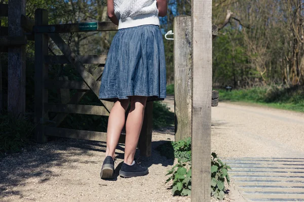 Donna in piedi vicino al cancello nella foresta — Foto Stock