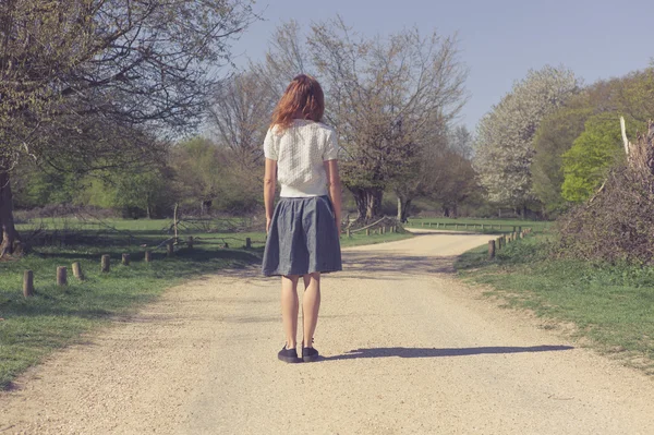 Woman standing on dirt road in forest — Stock Photo, Image