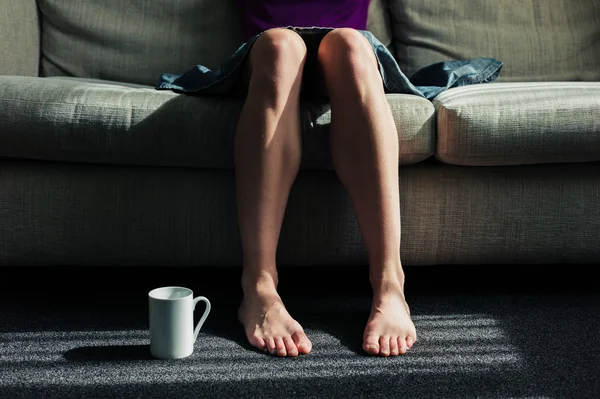 Kvinna sitter på soffan med mugg — Stockfoto
