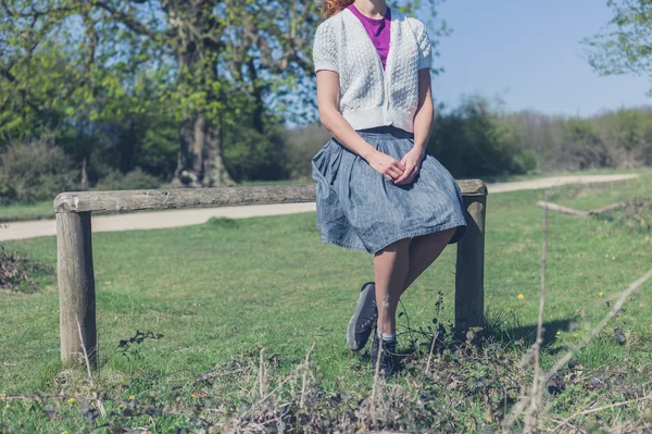 Femme assise sur une clôture dans la forêt — Photo