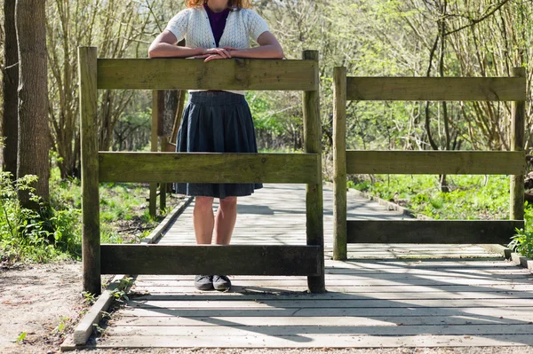 Vrouw permanent door poort in bos — Stockfoto