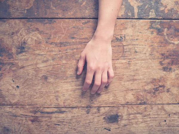 Mão feminina em uma mesa de madeira — Fotografia de Stock