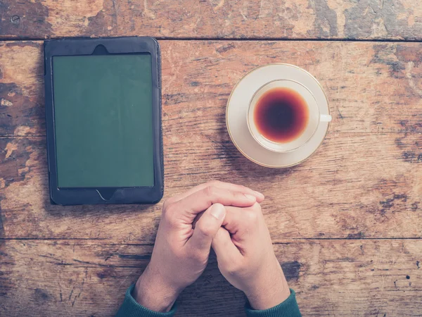 Male hands on wooden table with coffee and tablet — Stock Photo, Image