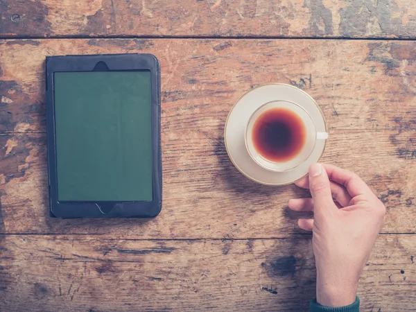 Mãos masculinas na mesa de madeira com café e tablet — Fotografia de Stock