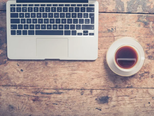 Laptop e xícara de café na mesa — Fotografia de Stock