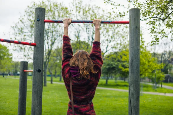 Woman doing pull ups in a park — Stock Photo, Image