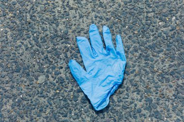 Blue latex glove on the ground outside