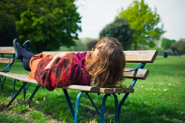 Vrouw liggen op een bankje in het park — Stockfoto