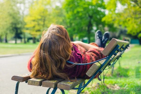 Mulher deitada em um banco no parque — Fotografia de Stock