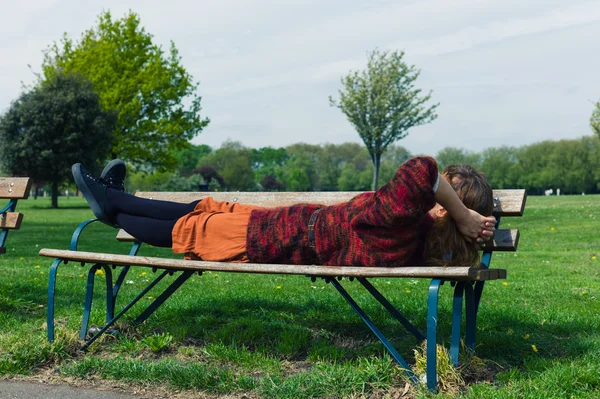 女人躺在公园的长椅上 — 图库照片