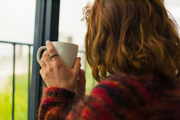 Kvinnan dricka te av th fönster — Stockfoto
