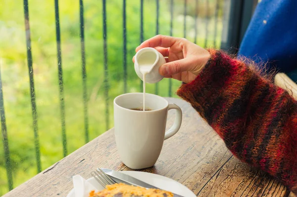 Woman pouring milk in her tea — Stock Photo, Image