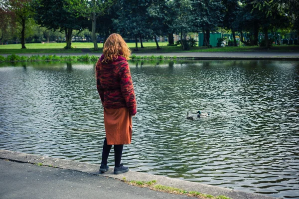 Donna in piedi vicino al laghetto in un parco — Foto Stock
