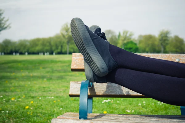Le gambe di una donna sdraiata su una panchina — Foto Stock