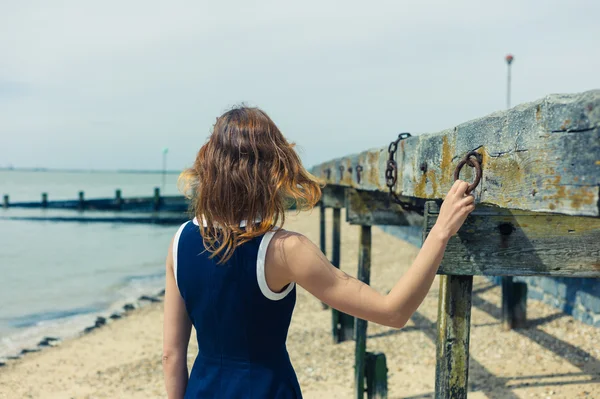 Young woman standing on beach with old wooden structure — Stock Photo, Image