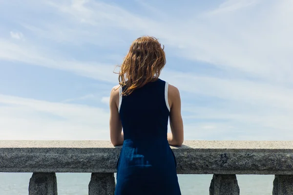 Mujer joven admirando el mar desde el paseo marítimo — Foto de Stock