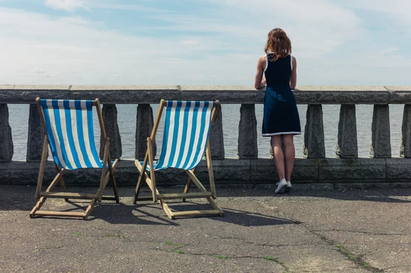 Mulher admirando o mar de passeio com espreguiçadeiras — Fotografia de Stock