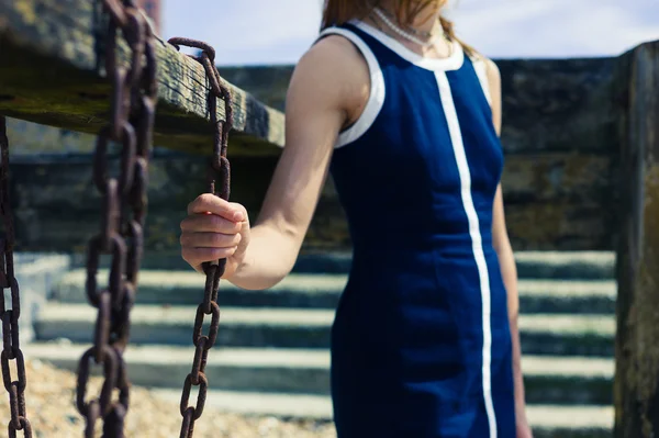 Junge Frau steht am Strand mit alter Holzkonstruktion — Stockfoto