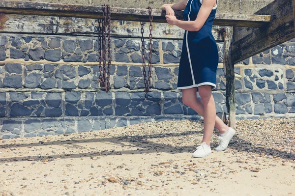 Young woman standing on beach with old wooden structure — Stock Photo, Image