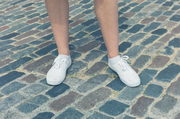 Jambes de femme debout sur la rue pavée — Photo