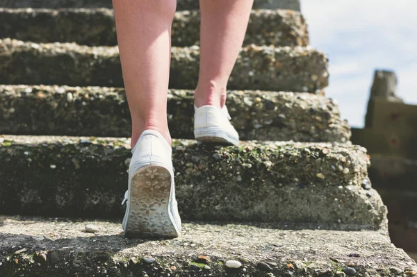 Woman walking up steps by the sea — Stock Photo, Image