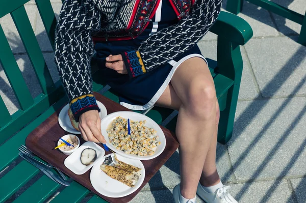 Женщина ест рыбу и коктейли на улице — стоковое фото